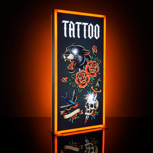 A vertical rectangular tattoo-style sign or poster with a glowing orange border, featuring the word "TATTOO" at the top and traditional tattoo artwork including a black panther, red roses, a blue bird, and a skull on a dark background.
