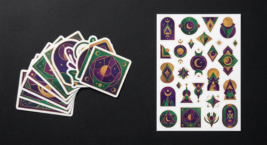 A flat lay comparison of individually die-cut custom stickers fanned out beside a full A4 sticker sheet, both featuring bold geometric and celestial designs in jewel tones on a dark textured surface.