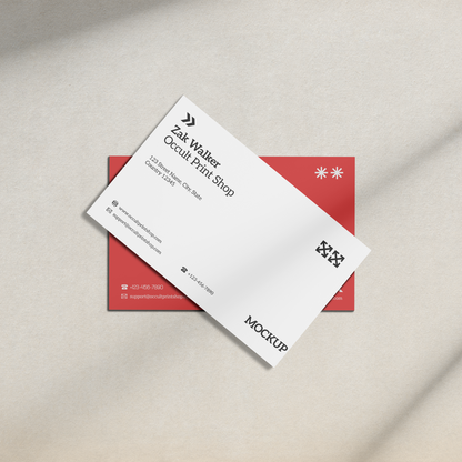 White business card with black text and red border on a beige surface.