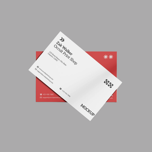 A white business card mockup layered diagonally over a red rectangular card, shown on a plain gray background. The front card includes black text, logos, and contact details, with the word MOCKUP printed near the bottom.