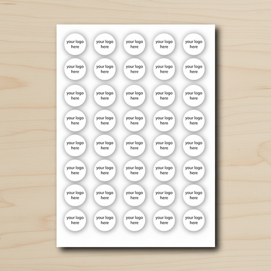 A sheet of round sticker labels with placeholder text 'your logo here' printed on a white card, placed on a light wood surface.